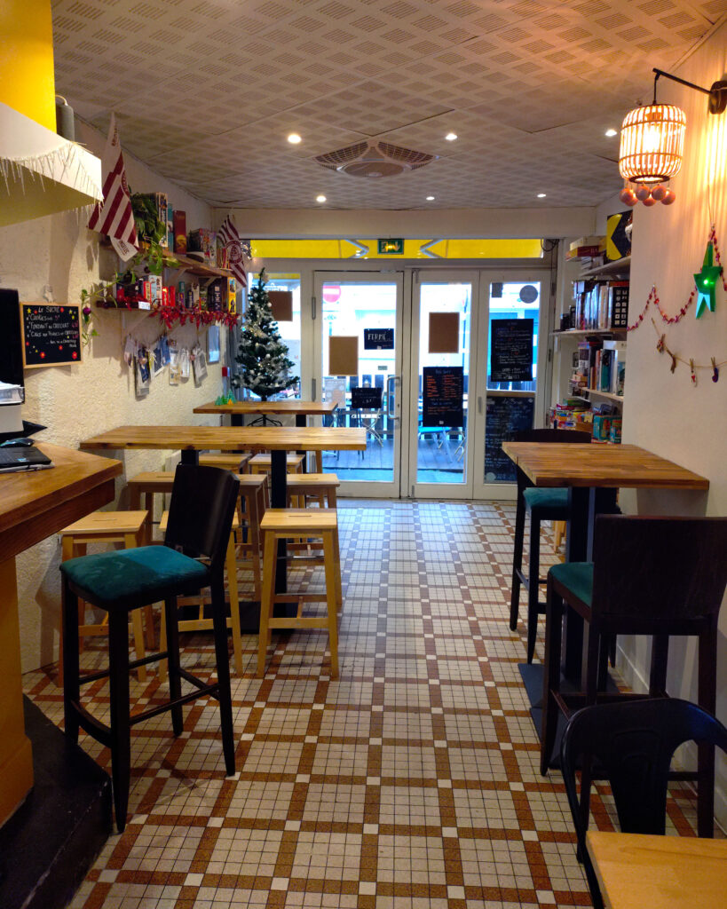 Intérieur cosy et coloré du bar à jeux L’OCNI à Bordeaux Saint-Augustin, avec des étagères remplies de jeux, des tables conviviales et une décoration rétro. Idéal pour des soirées jeux près de Mérignac et du CHU.